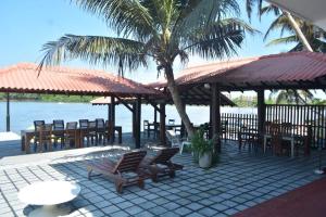 a patio with tables and chairs and a palm tree at Luthmin River View Hotel in Alutgama
