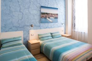 2 letti in una camera da letto con pareti blu di Rooms Boutique Carducci a Trieste
