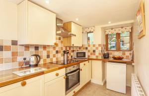 a kitchen with white cabinets and a stove top oven at Hedgehog Cottage Wheddon Cross in Wheddon Cross