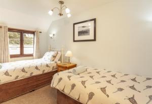 a bedroom with two beds and a window at Hedgehog Cottage Wheddon Cross in Wheddon Cross