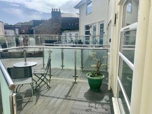a balcony with a potted plant and a table and chairs at Waterside apartment, central Falmouth, Vi-spring king bed, gated parking in Falmouth