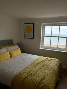 a bedroom with a bed with a yellow comforter and a window at Georgian Townhouse on the beach in Worthing