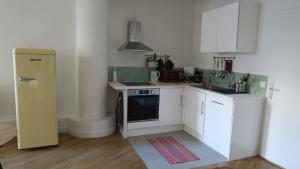 a small kitchen with white cabinets and a refrigerator at Appartement d'architecte in Marseille +2 photos