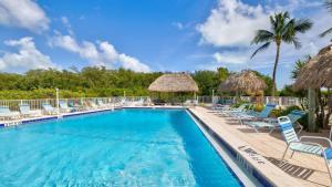 a pool with chairs and umbrellas at a resort at Whispering Palms Sea Gulls 210 in Key Largo
