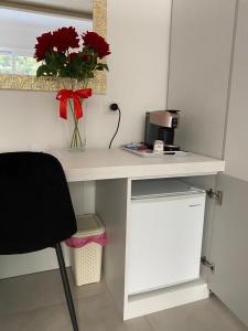 a white desk with a vase of red flowers on it at SANGIOVANNI rooms in Mandatoriccio Marina