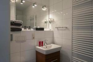 a white bathroom with a sink and a mirror at Gästehaus Orion - Wohnung 9 in Spiekeroog