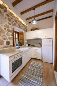 a kitchen with white appliances and a stone wall at Apsinthium in Kalymnos +8 photos