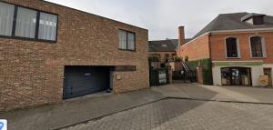 a brick building with a garage with a door at Apartment de Kerk in Sint-Gillis-Waas