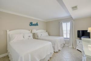 2 Betten in einem weißen Zimmer mit einem TV in der Unterkunft The Breakers 44 by Vacation Homes Collection in Orange Beach