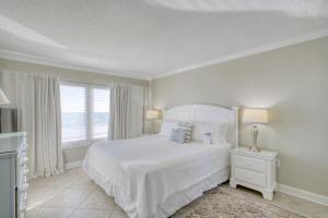 ein weißes Schlafzimmer mit einem Bett und einem Fenster in der Unterkunft The Breakers 44 by Vacation Homes Collection in Orange Beach