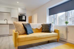 a yellow couch with pillows on it in a kitchen at No 4 at The Rocketroom Apartments in Berwick-Upon-Tweed