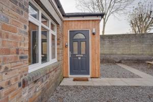 a house with a blue door and a brick wall at No 4 at The Rocketroom Apartments in Berwick-Upon-Tweed