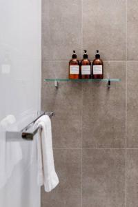 tres botellas de whisky sentadas en un estante en un baño en Re-Imagined Victorian Terrace Home, en Melbourne 26 fotos más