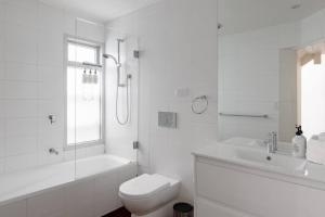 a white bathroom with a toilet and a sink at Luxury On Lygon, Victorian Terrace in Melbourne +12 photos