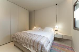 a bedroom with a bed with white walls and a window at Vivelorural Villa Óscar, Maspalomas in San Bartolomé de Tirajana