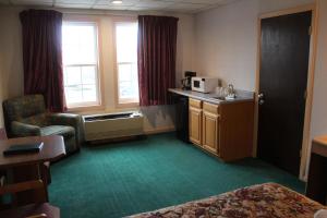 Pokój z łóżkiem, krzesłem i kuchenką mikrofalową w obiekcie Anchorage Inn Burlington w mieście Burlington