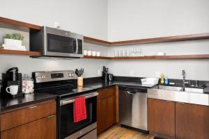 a kitchen with stainless steel appliances and wooden cabinets at Chic Loft in Peoria Warehouse District in Peoria
