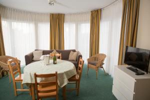 a living room with a table with a couch and a television at Apparthotel De Wielingen in Middelkerke
