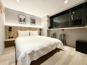 a bedroom with a white bed and a large window at N2 Hotel in Taichung