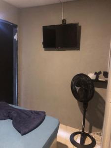 a bedroom with a fan and a tv on the wall at Peró Beach Hospedaria in Cabo Frio