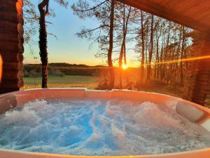 Les FargesMagnifique chalets en rondins avec ou sans spa et Tipis en plaine Nature Environnement ressourçant au calme vue imprenable Lascaux SPA non disponible juillet et aout的按摩浴缸,背面是日落