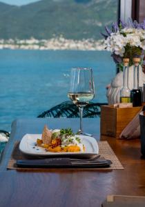 a plate of food and a glass of wine on a table at Luxury Sea Residence by Kristina in Tivat