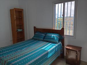 a bedroom with a bed with a blue comforter and a window at Baafeh Beach in Sanyang