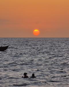 two people swimming in the ocean at sunset at Pousada Villa Xaréu in Barra Grande