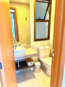 een badkamer met een toilet, een wastafel en een spiegel bij Flat completo próximo ao Rio centro e Arena Carioca in Rio de Janeiro