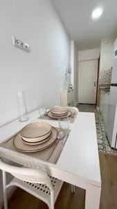 a white kitchen with plates on a white table at Estudio Pastora in Torremolinos