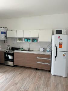 a kitchen with a white refrigerator and wooden floors at Casa Silva in Las Grutas