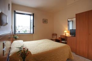 um quarto de hotel com uma cama e uma janela em Albergo La Rocca em Assis
