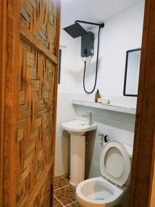 a bathroom with a toilet and a wooden door at Bloom Siargao - Cozy Villa in Pacifico in San Isidro