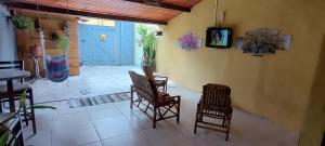 a room with two chairs and a tv on a wall at Hospeda Maresias quartos in Maresias