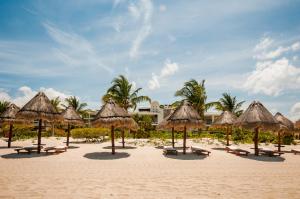 ein Strand mit vielen Strohschirmen und -stühlen darauf in der Unterkunft Ph en resort de lujo con acceso a la playa y todas las amenidades in Cancún
