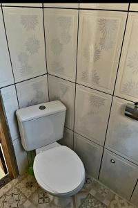 a bathroom with a toilet and a tiled wall at BOIPEBA Cantinho do Mirko 1 in Cairu