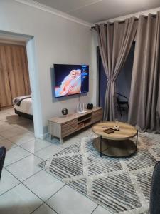 a living room with a tv and a coffee table at Cozy home at The Blyde in Pretoria +4 photos