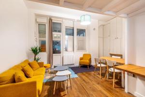 a living room with a yellow couch and a table at Joli - Lovely studio Paris in Paris