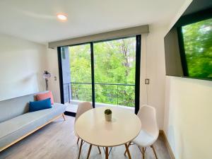 a living room with a table and chairs and a window at Second Home Darwin in Mexico City
