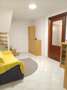 a living room with a yellow bed and a door at Hiša BUNAR in Jablanac