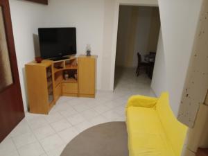 a living room with a yellow couch and a television at Hiša BUNAR in Jablanac