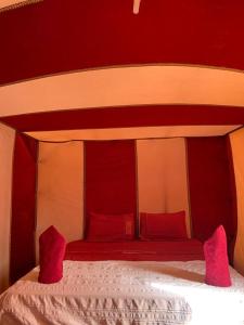 un letto rosso e bianco con cuscini rossi di Camp atlantic chegaga a M'Hamid