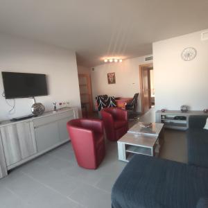 a living room with red chairs and a tv at VILLAS COSETTE Apartamento CAMILLE in Sant Feliu de Guixols