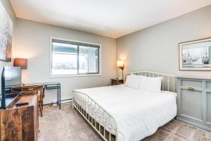 a bedroom with a bed and a desk and a window at Condo with Balcony and Views - Steps to Ski Shuttle! in Fraser +25 photos