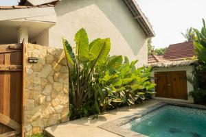 ein Pool vor einem Haus mit Pflanzen in der Unterkunft Villa Trembesi in Kuta Lombok