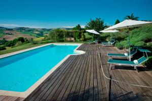 einen Pool mit Stühlen und Sonnenschirmen auf einer Holzterrasse in der Unterkunft Casal dei Fichi in Francavilla dʼEte