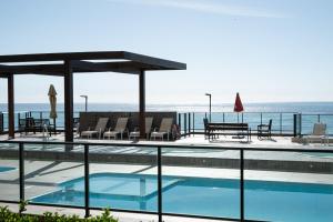 ein Swimmingpool mit Blick auf das Meer in der Unterkunft Aptos completo com vista mar pé na areia em Barra Velha em condomínio Resort com Spa, Piscina, quadra de futebol, Sala de jogos, brinquedoteca, Complexo com diversos comércios in Barra Velha