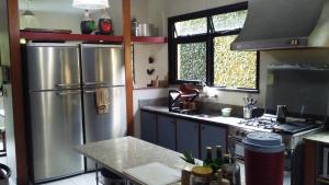 Una cocina con frigorífico de acero inoxidable y fregadero. en REB Casa Itanhangá, en Río de Janeiro