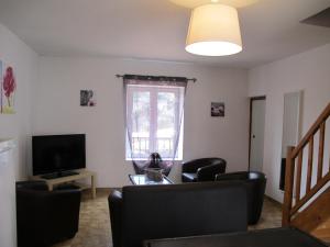 a living room with a tv and a couch and chairs at Cairenou Location in Saint-Martin-dʼArdèche