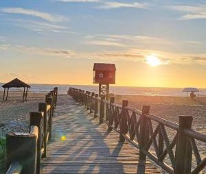 a wooden boardwalk leading to the beach with the sunset at Grussaí houses in São João da Barra